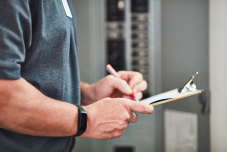 person holding a clipboard at electrical panel